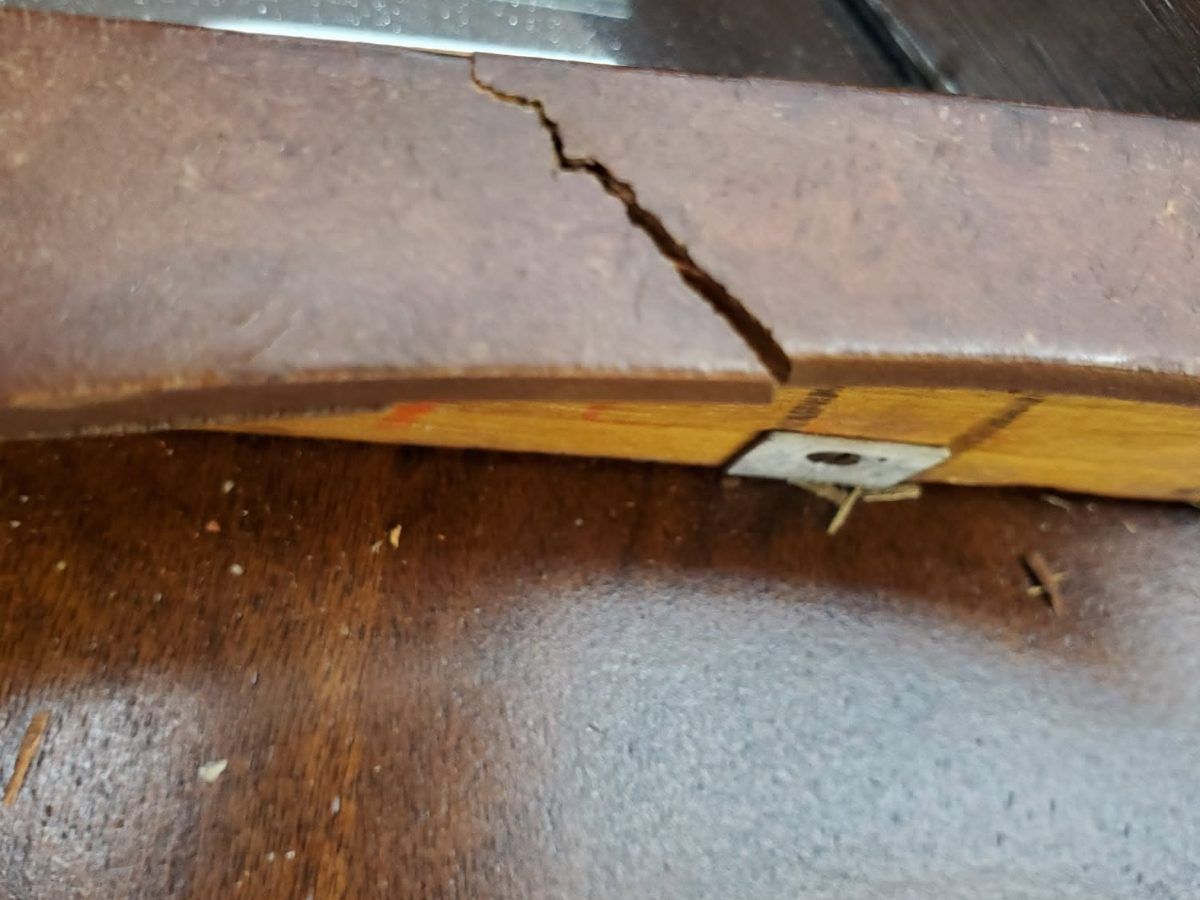 A split wooden rail with an earlier repair plate that has failed, the kind of damage recorded in an inspection report.