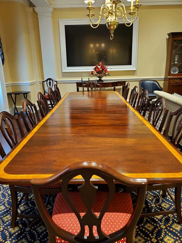 A long mahogany conference table with satinwood banding, refinished to a mirror gloss in a formal boardroom.